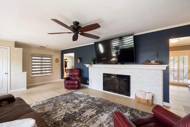 living room with a brick fireplace, ceiling fan, ornamental molding, and wood finished floors