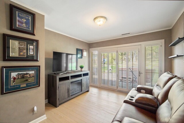 living area featuring a wealth of natural light, light wood-style floors, and crown molding