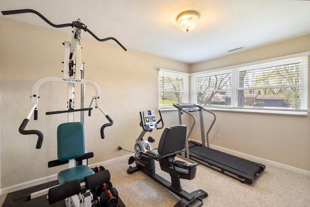 exercise area with visible vents, carpet flooring, and baseboards