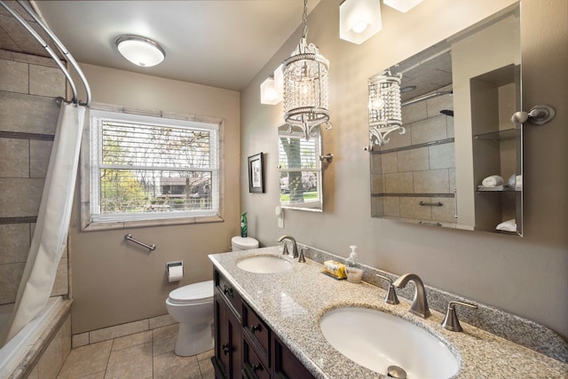 bathroom featuring tiled shower / bath, an inviting chandelier, toilet, and a sink
