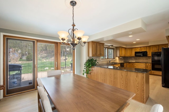 dining area with light wood-type flooring, an inviting chandelier, and recessed lighting