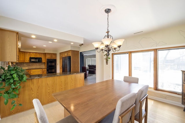 dining area featuring light wood-type flooring, recessed lighting, an inviting chandelier, and a healthy amount of sunlight