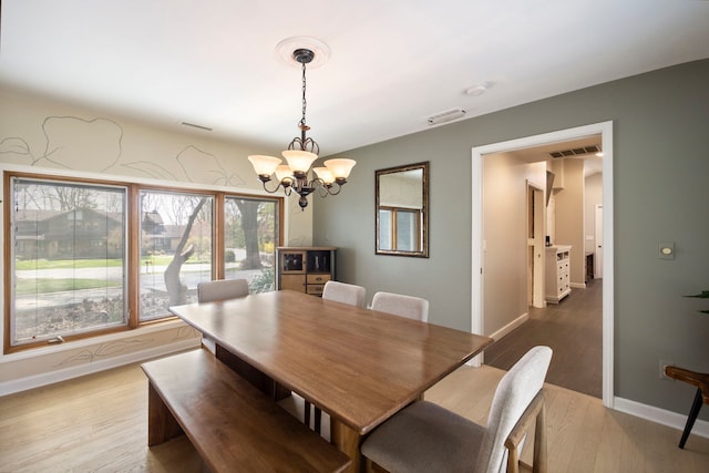 dining area featuring baseboards, visible vents, light wood-type flooring, and an inviting chandelier