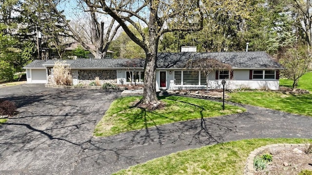 ranch-style house with a front lawn, aphalt driveway, and an attached garage