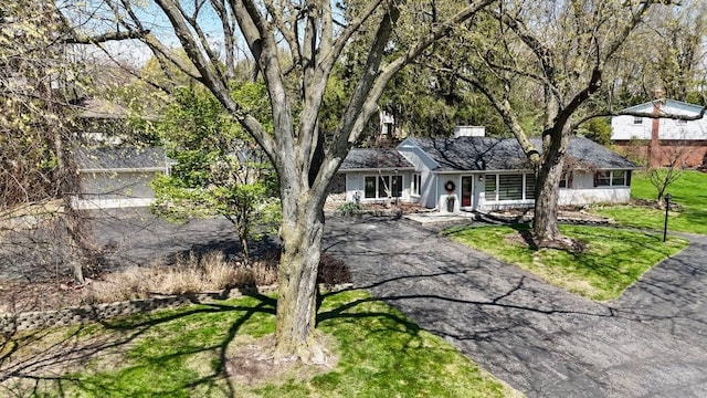 view of front facade featuring covered porch, a front lawn, and driveway