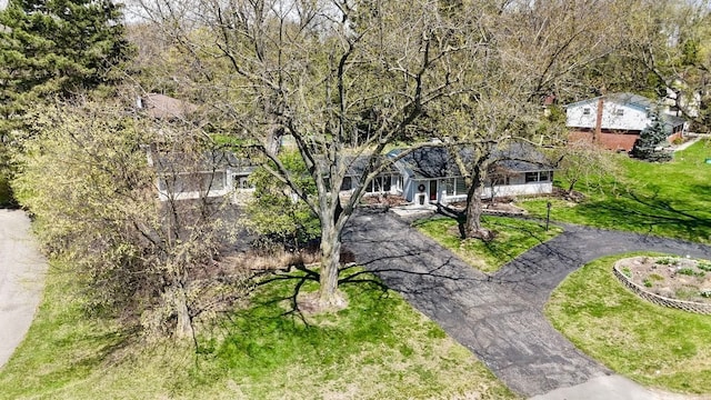 view of home's community with aphalt driveway and a lawn