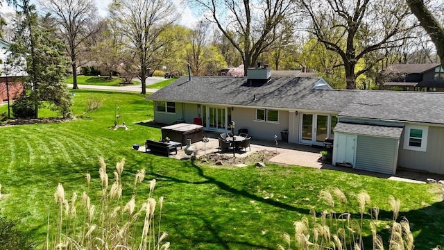 back of property featuring a patio area, an outbuilding, a lawn, a hot tub, and french doors