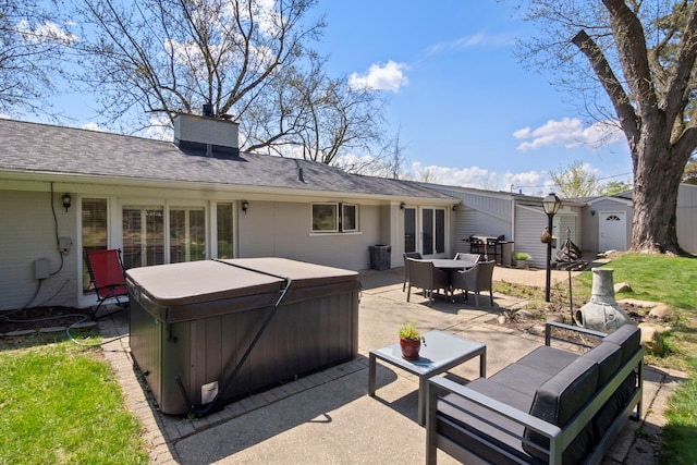 rear view of house with outdoor dining area, a shed, a hot tub, and a patio area