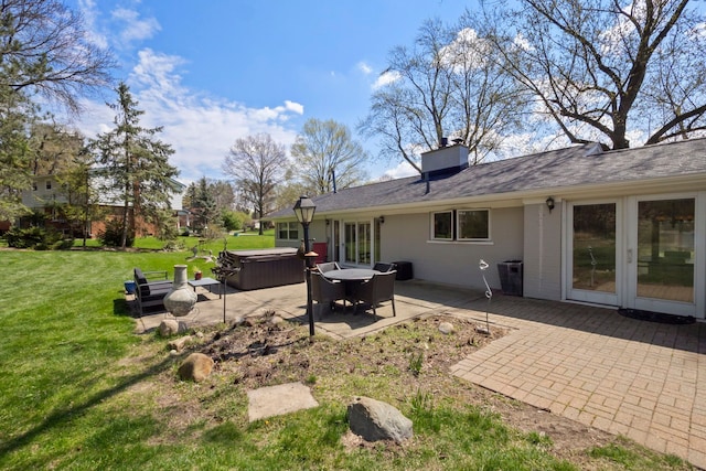rear view of house featuring a patio, a chimney, a hot tub, a lawn, and french doors