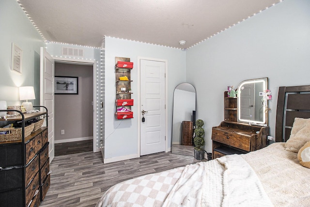 bedroom with baseboards, wood finished floors, and visible vents