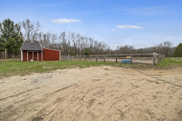 view of yard with fence, a rural view, an outbuilding, and a barn