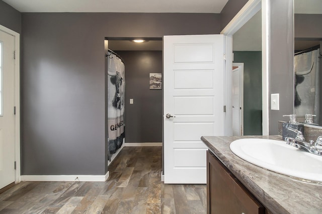 bathroom featuring a shower with shower curtain, baseboards, and vanity