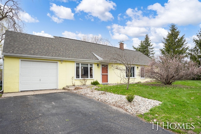 view of front of home featuring an attached garage, roof with shingles, a front yard, and aphalt driveway