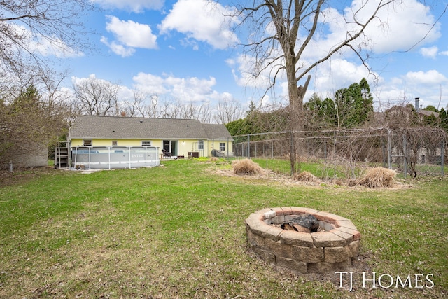 rear view of property with a fire pit, a lawn, an outdoor pool, and fence