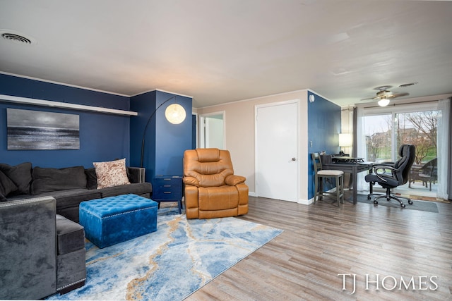 living area with baseboards, wood finished floors, visible vents, and a ceiling fan