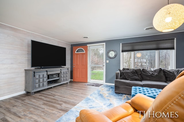 living room with baseboards, ornamental molding, wood finished floors, and visible vents