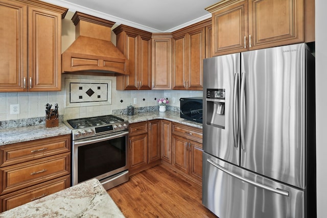 70799 Fisher Rd, Bruce, MI 48065 - kitchen featuring backsplash, wood finished floors, brown cabinetry, appliances with stainless steel finishes, and custom exhaust hood