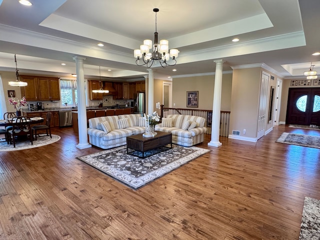 70799 Fisher Rd, Bruce, MI 48065 - living area with a tray ceiling, a notable chandelier, ornate columns, and dark wood finished floors