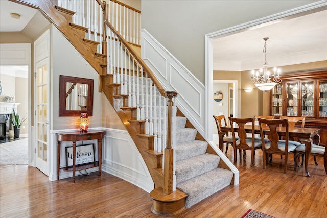 8504 Riverwalk Dr, Fenton, MI 48430 - stairs featuring wood finished floors, a chandelier, a decorative wall, and ornamental molding