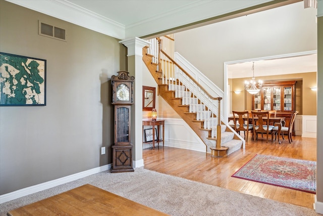 8504 Riverwalk Dr, Fenton, MI 48430 - stairs featuring a chandelier, ornamental molding, wood finished floors, wainscoting, and carpet