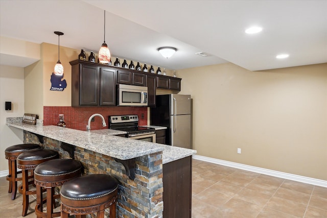 8504 Riverwalk Dr, Fenton, MI 48430 - kitchen with stainless steel appliances, a kitchen breakfast bar, dark brown cabinetry, a peninsula, and baseboards