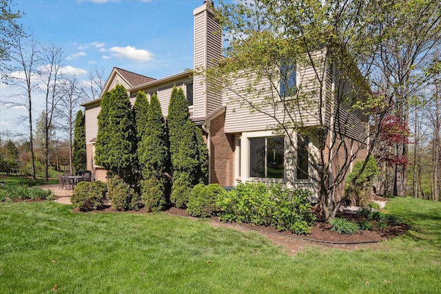 8504 Riverwalk Dr, Fenton, MI 48430 - view of property exterior featuring a chimney, a yard, a patio area, and brick siding