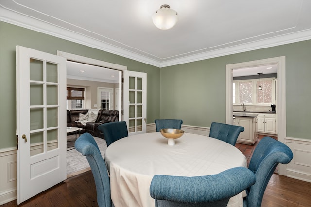 dining space featuring crown molding, healthy amount of natural light, french doors, a wainscoted wall, and dark wood-type flooring