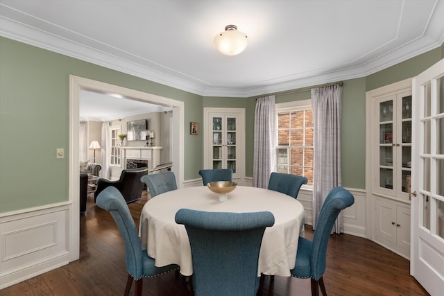 dining room featuring ornamental molding, french doors, a fireplace, wainscoting, and dark wood finished floors