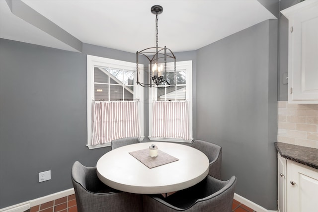 dining room featuring a chandelier, baseboards, and dark tile patterned flooring