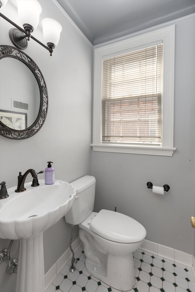 bathroom featuring toilet, baseboards, and a sink