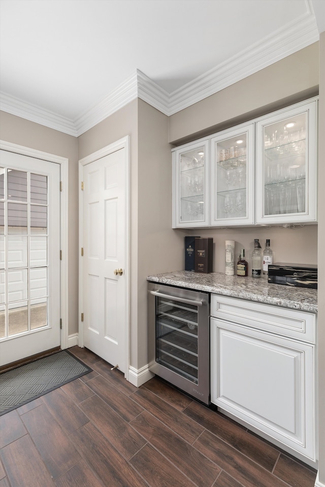 indoor dry bar with beverage cooler, dark wood-style floors, baseboards, and crown molding
