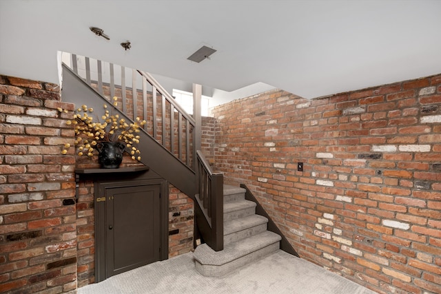 stairs with brick wall and carpet
