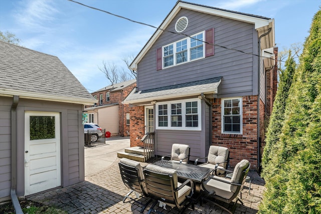 rear view of property with a patio area, brick siding, and outdoor dining space