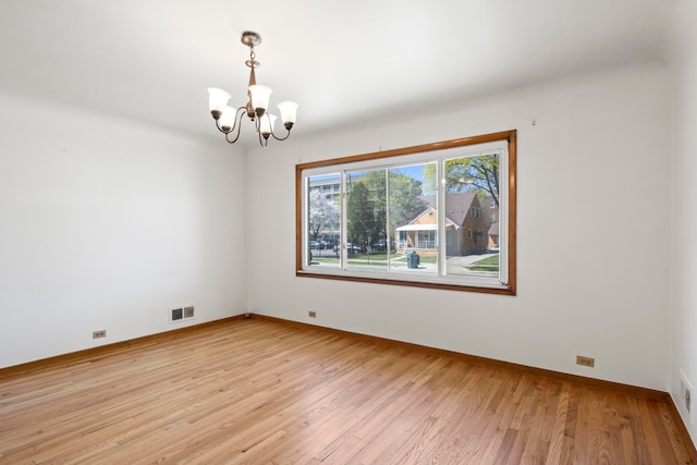 unfurnished room with light wood-style floors, visible vents, baseboards, and an inviting chandelier