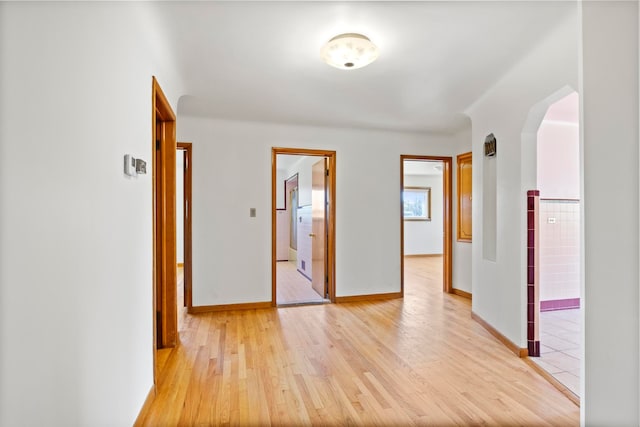 corridor featuring baseboards and light wood finished floors