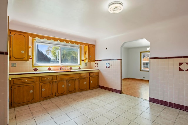 kitchen with brown cabinets, tile walls, and a sink