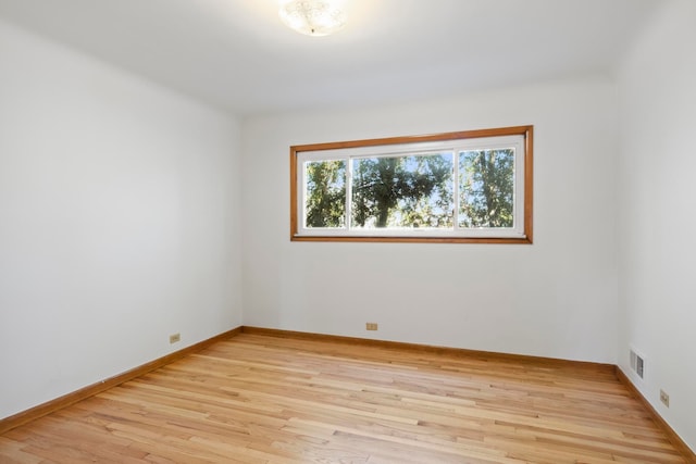 empty room featuring baseboards, light wood finished floors, and visible vents
