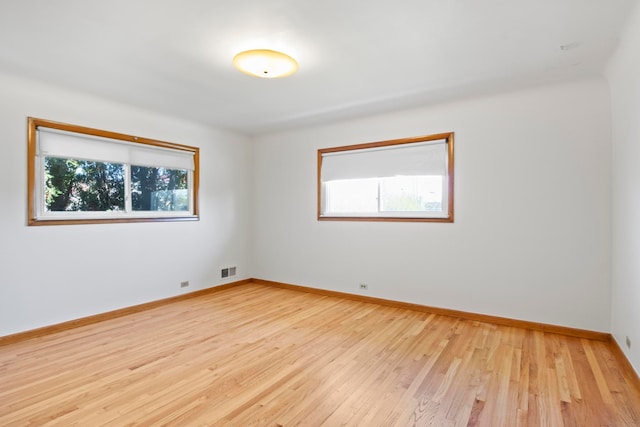 unfurnished room with baseboards, visible vents, and light wood-style floors