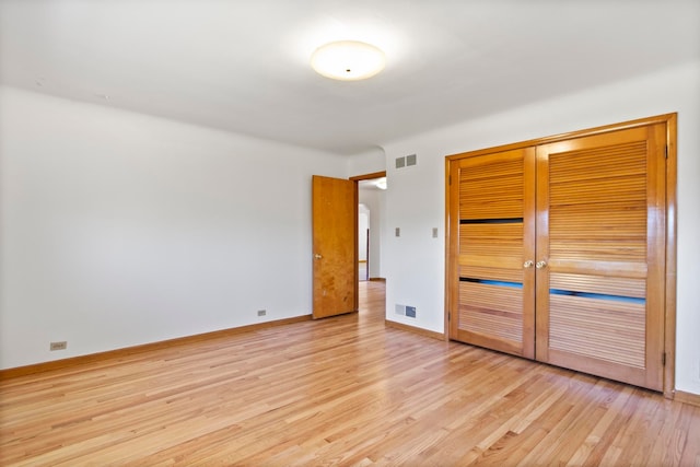 unfurnished bedroom featuring baseboards, visible vents, light wood finished floors, and a closet