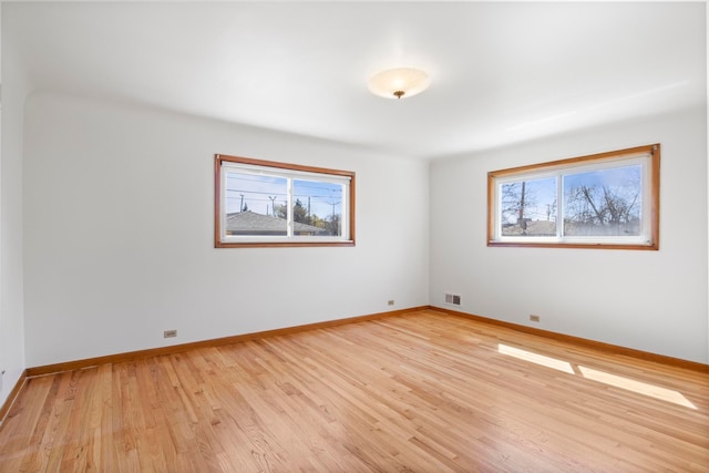 spare room featuring light wood-style flooring, a healthy amount of sunlight, and baseboards
