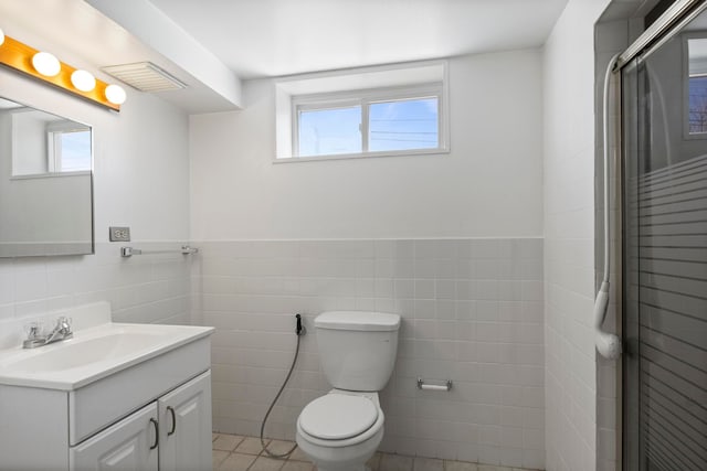full bathroom with tile walls, a healthy amount of sunlight, toilet, and vanity