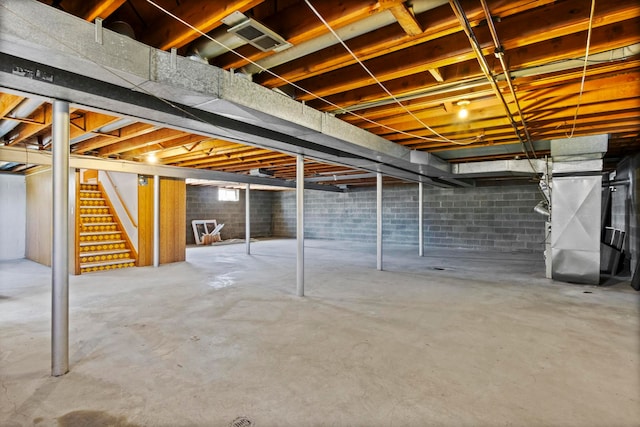 unfinished basement featuring heating unit, stairs, and visible vents