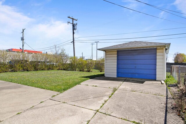 detached garage with fence and concrete driveway