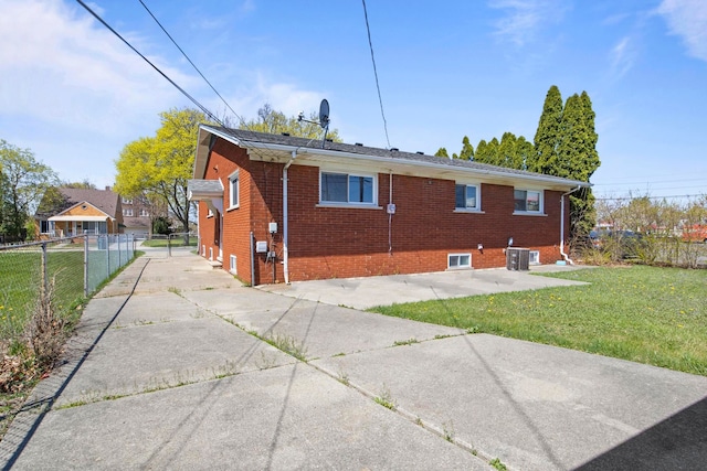 rear view of property with a lawn, central air condition unit, brick siding, and fence