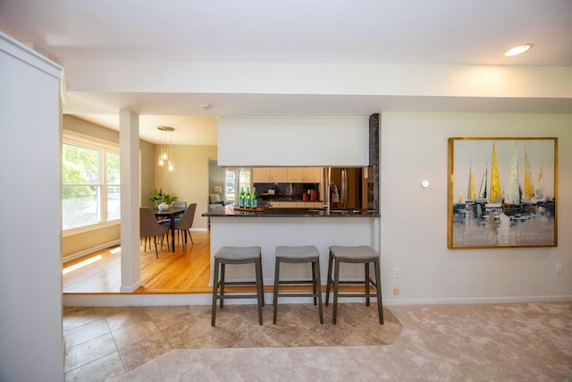 2015 Rugby Ct, Ann Arbor, MI 48103 - kitchen featuring dark countertops, baseboards, a breakfast bar, a peninsula, and stainless steel fridge with ice dispenser