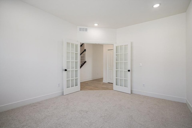 carpeted empty room featuring recessed lighting, visible vents, baseboards, and french doors