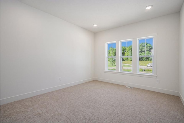 spare room featuring light colored carpet, baseboards, visible vents, and recessed lighting