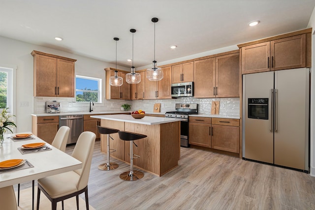 kitchen featuring backsplash, light wood-type flooring, a center island, appliances with stainless steel finishes, and a breakfast bar area