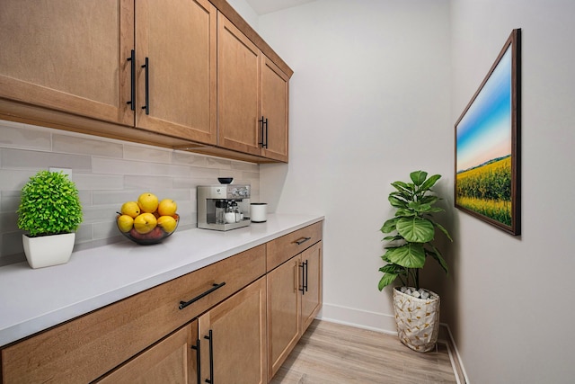 bar featuring light wood-type flooring, baseboards, and tasteful backsplash