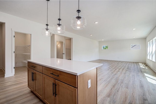 kitchen with light wood finished floors, a center island, pendant lighting, brown cabinetry, and light countertops